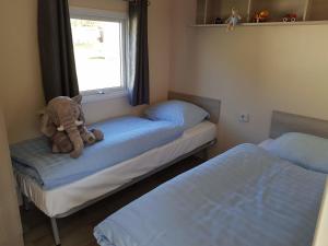 ein Teddybär sitzt auf einem Bett in einem Schlafzimmer in der Unterkunft Mobilheim Bachvogel am Kransburger See 552 in Kransburg