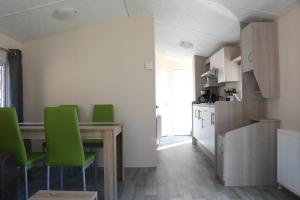 eine Küche mit einem Tisch und grünen Stühlen im Zimmer in der Unterkunft Mobilheim Bachvogel am Kransburger See 552 in Kransburg