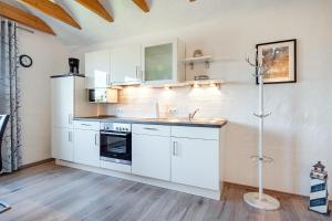 a white kitchen with a sink and a refrigerator at Ferienwohnung Ebbe mit Loggia und schönem Ausblick am Badesee Tannenhausen in Aurich