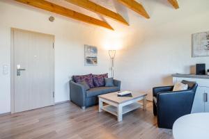 a living room with a couch and a table at Ferienwohnung Ebbe mit Loggia und schönem Ausblick am Badesee Tannenhausen in Aurich