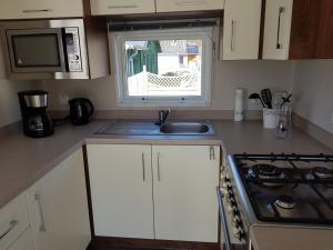 a kitchen with a sink and a stove and a window at Luxusmobilheim Seehund am Kransburger See 551 in Kransburg