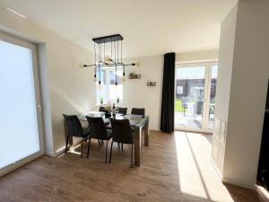 a dining room with a table and black chairs at Haus Leni in Butjadingen +17 photos