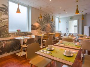 a restaurant with tables and chairs and a large window at Hotel Kyriad Lamballe in Lamballe