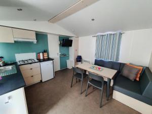 a room with a kitchen and a table with chairs at Campingland Ostsee - Mobilheim 155Meerluft in Schashagen