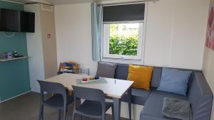 a living room with a blue couch and a table at Campingland Ostsee - Mobilheim 155Meerluft in Schashagen