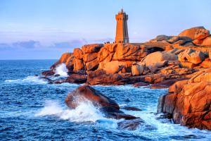 a lighthouse on a rocky shore with the ocean at Appartement T2, RDJ, 2 étoiles, Vue mer panoramique, Côte de Granit Rose in Perros-Guirec