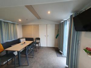 Un comedor con mesa y sillas y ventanas. en Campingland Ostsee - Mobilheim 61Meeresstille, en Schashagen
