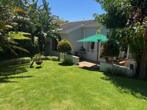 a yard with a house with a green lawn at GRACE COTTAGE Charming 2 Bed en-suite Cottage with Solar in Cape Town