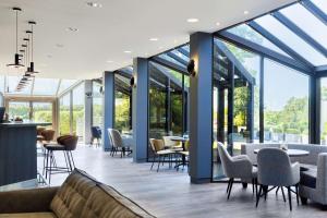 a restaurant with glass walls and tables and chairs at NH Luxembourg Airport in Luxembourg +37 photos