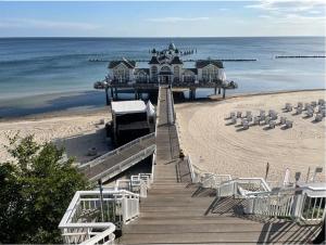 ein Gebäude am Strand mit Stühlen und einem Pier in der Unterkunft Studio Ostseewind Residenz Seeblick in Ostseebad Sellin