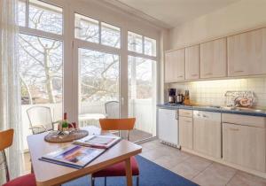 eine Küche mit einem Tisch und einigen Stühlen und Fenstern in der Unterkunft Studio Ostseewind Residenz Seeblick in Ostseebad Sellin