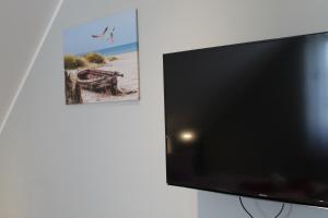 een flatscreen-tv aan een muur met een foto bij Villa Aquila Luxus-Maisonette Ferienträume Dachterrasse in Göhren-Lebbin +13 foto's
