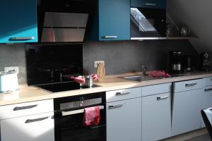 a kitchen with white cabinets and a black stove top oven at Villa Aquila Luxus-Maisonette Ferienträume Dachterrasse in Göhren-Lebbin