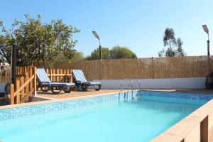 a swimming pool with two lounge chairs next to a fence at Castro's guesthouse in Viana do Castelo