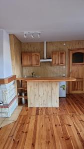 a kitchen with wooden cabinets and a wooden floor at Boszkowski Azyl in Boszkowo-Letnisko
