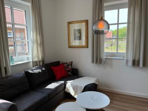 a living room with a black couch and two tables at Martje in Lastrup