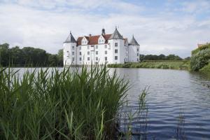 a large white castle sitting on top of a lake at Tante Kamps Hus - Uriges Häuschen mit Garten und Geschichte in Bönstrup