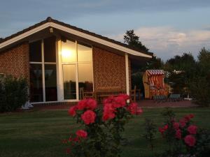 una casa de ladrillo con una ventana y flores en el patio en Haus an der Pferdekoppel C eingezäunt 130m, en Fehmarn