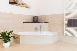 a white tub in a bathroom with a plant at Wellnesshaus "Wind" in Fehmarn