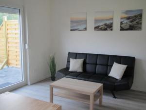 a living room with a black couch and a coffee table at Barons Ferienappartement A in Dargun +5 photos