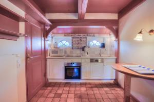 una cucina con mobili bianchi e un forno a piano cottura di S3 im Friesenhaus Sara a Wenningstedt