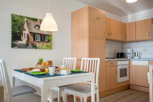 a kitchen with a white table and white chairs and a table and a table at Knusthof Lafrenz - Sundblick in Fehmarn