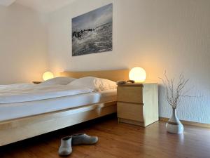 a bedroom with a bed with two lamps and shoes on the floor at Ferienwohnung Ost in Fehmarn