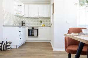eine Küche mit weißen Schränken und einem Holzboden in der Unterkunft Villa Fortuna - Suite mit Terrasse in Ostseebad Sellin