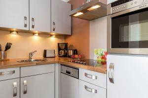 une cuisine avec des armoires blanches et un évier dans l'établissement ancora Marina Haus 1 Nr 10, Typ 4, à Neustadt in Holstein