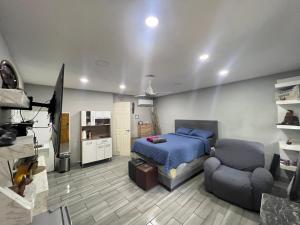 a bedroom with a bed and a couch and a television at Estudio con funciones inteligentes AC full moderno in San Salvador