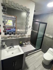 a bathroom with a sink and a toilet and a mirror at Estudio con funciones inteligentes AC full moderno in San Salvador +21 photos