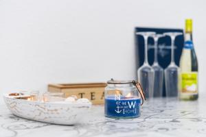 a candle and a bowl on a table with wine bottles at Ferienwohnungen Haus Boje "Scholle" in Neuharlingersiel