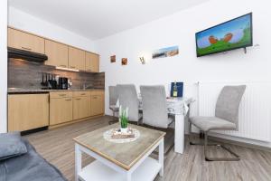 a living room with a couch and a table and a kitchen at Ferienwohnungen Haus Boje "Scholle" in Neuharlingersiel