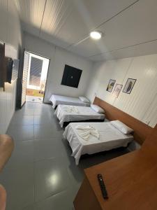 a room with three beds and a television at Inocência Park Hotel in Inocência