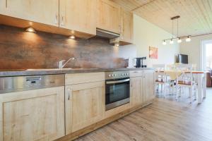a kitchen with wooden cabinets and a sink and a stove at Ferienhof Büdlfarm - Haus in Fehmarn