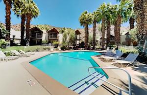Indian Wells Mtn Cove with Kitchen Living Room Patio Firepit BBQ Tennis Stadium في إينديان ويلس: حمام سباحة مع كراسي وأشجار النخيل