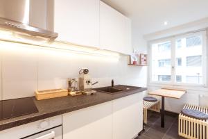 a kitchen with white cabinets and a sink and a window at Boutique Apartment im trendigen Quartier am Rhein in Basel