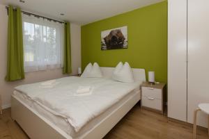 a bedroom with a white bed with a green wall at Ferienhaus Biber im Sternenpark in Lochow