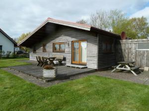 a wooden cabin with a picnic table and a picnic table at Diekkieker in Wurster Nordseeküste