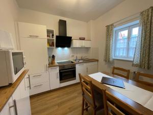 a kitchen with white cabinets and a table with a laptop at Apartment mit Terrasse No3 in Quedlinburg