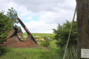 a rusted out object in a field with a tree at Ferienhaus Strandnah - Wohnung 2 in Otterndorf