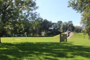 a park with a playground with a slide in the grass at Ferienhaus Strandnah - Wohnung 2 in Otterndorf +5 photos