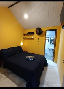 a bedroom with a black bed and a yellow wall at Casa do Guilherme in Paranaguá