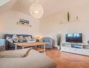 a living room with a couch and a tv at Kapitänshaus Kittler - Sehnsucht - FeWo 1OG - DG in Wiek auf Rügen 
