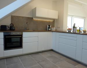 eine Küche mit weißen Schränken und einer Spüle in der Unterkunft Ferienwohnung am Wald in Goslar