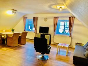 a living room with a chair and a table and windows at Ferienwohnung Villa Wolke in Sankt Wendel