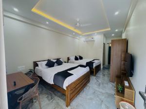 a bedroom with two beds and a desk and a television at Thamarassery INN luxury and budget Rooms in Thamarassery