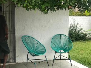 two green chairs sitting next to a wall at Casa Jasmim in Imbituba