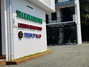 a white building with signs on the side of it at Thamarassery INN luxury and budget Rooms in Thamarassery