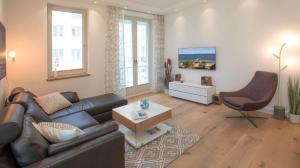 ein Wohnzimmer mit einem Ledersofa und einem Stuhl in der Unterkunft SPA Apartment FIRST Sellin in Ostseebad Sellin